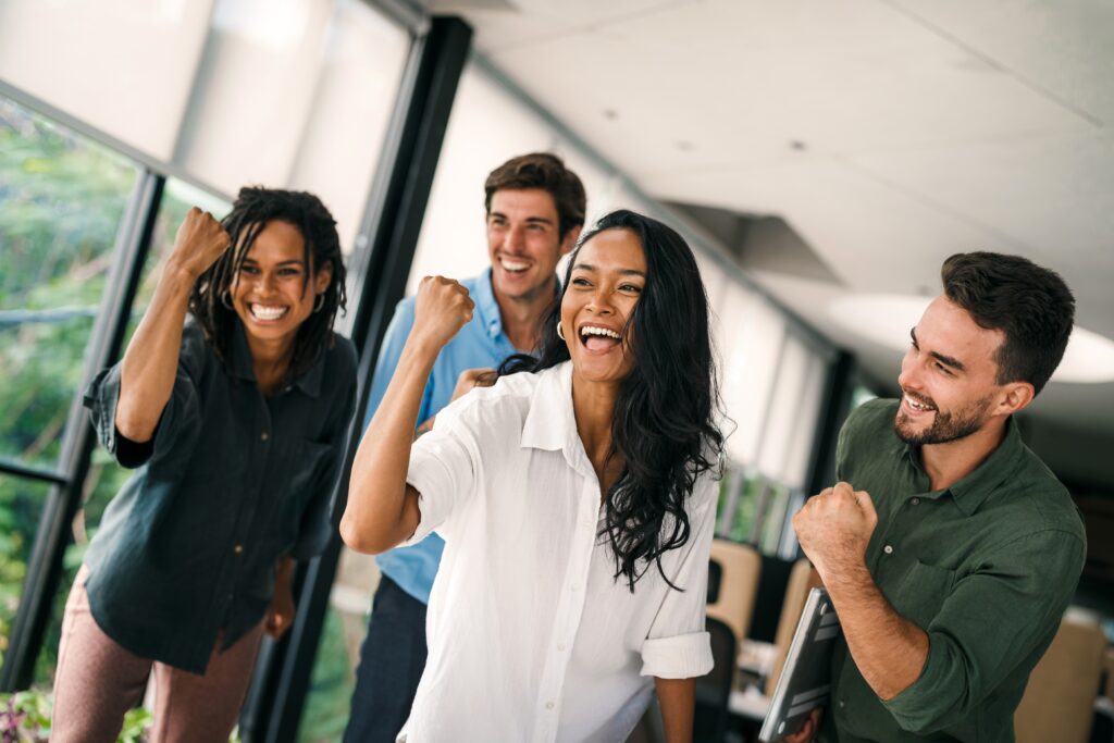 A direct sales team with raised fists and smiling faces.